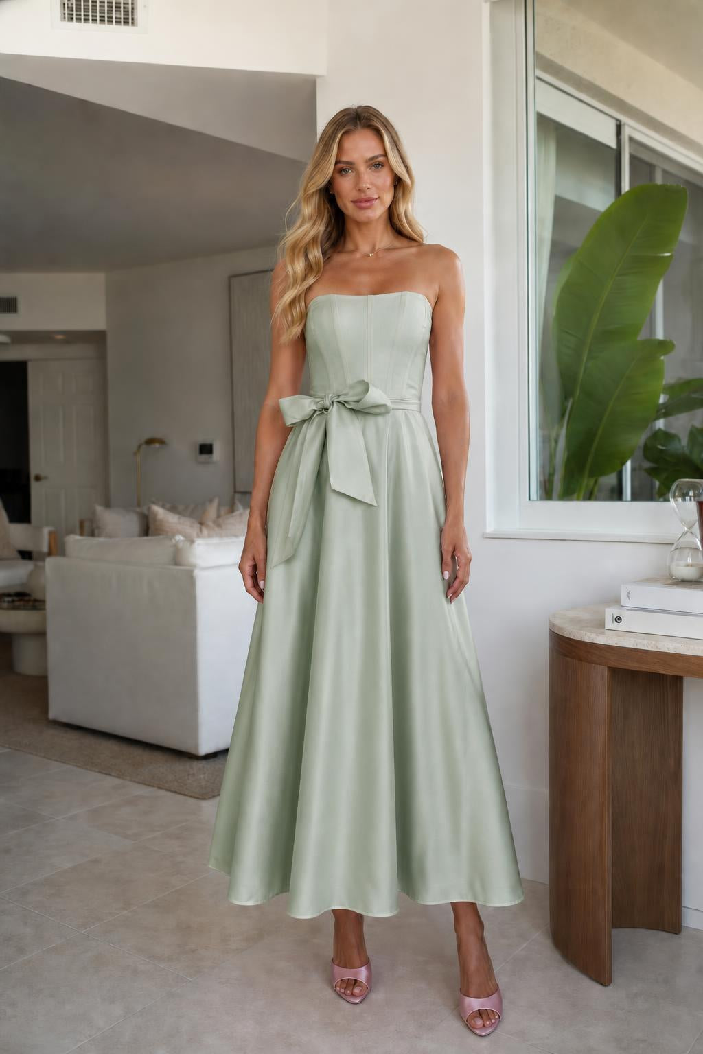Model wearing sage green strapless bow waist midi dress
