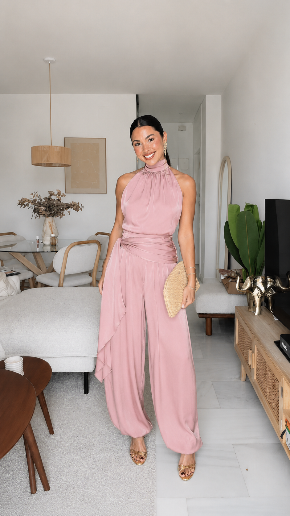 Blush pink halter jumpsuit with flowing wide legs and clutch