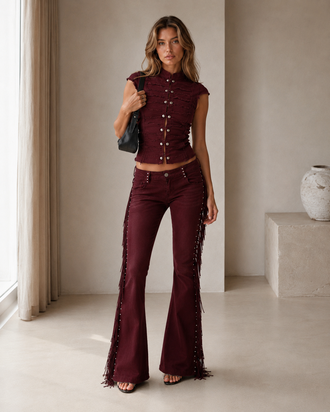 Model wearing a burgundy button-front crop top and matching fringe flare pants