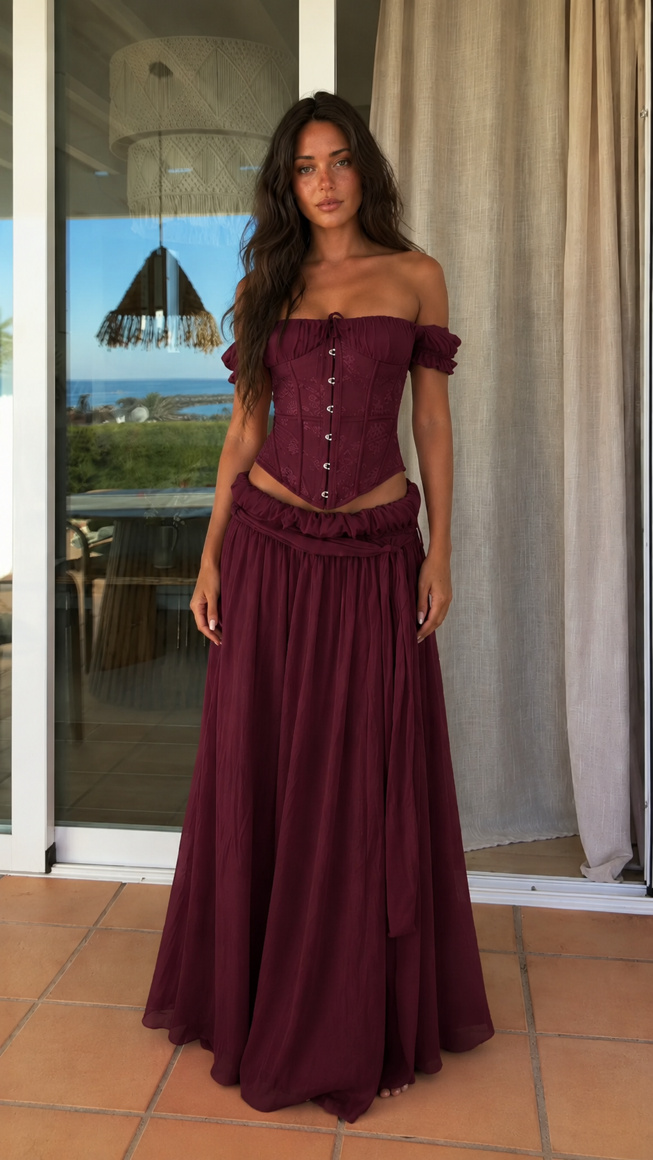 Front view of burgundy off shoulder corset top and maxi skirt set
