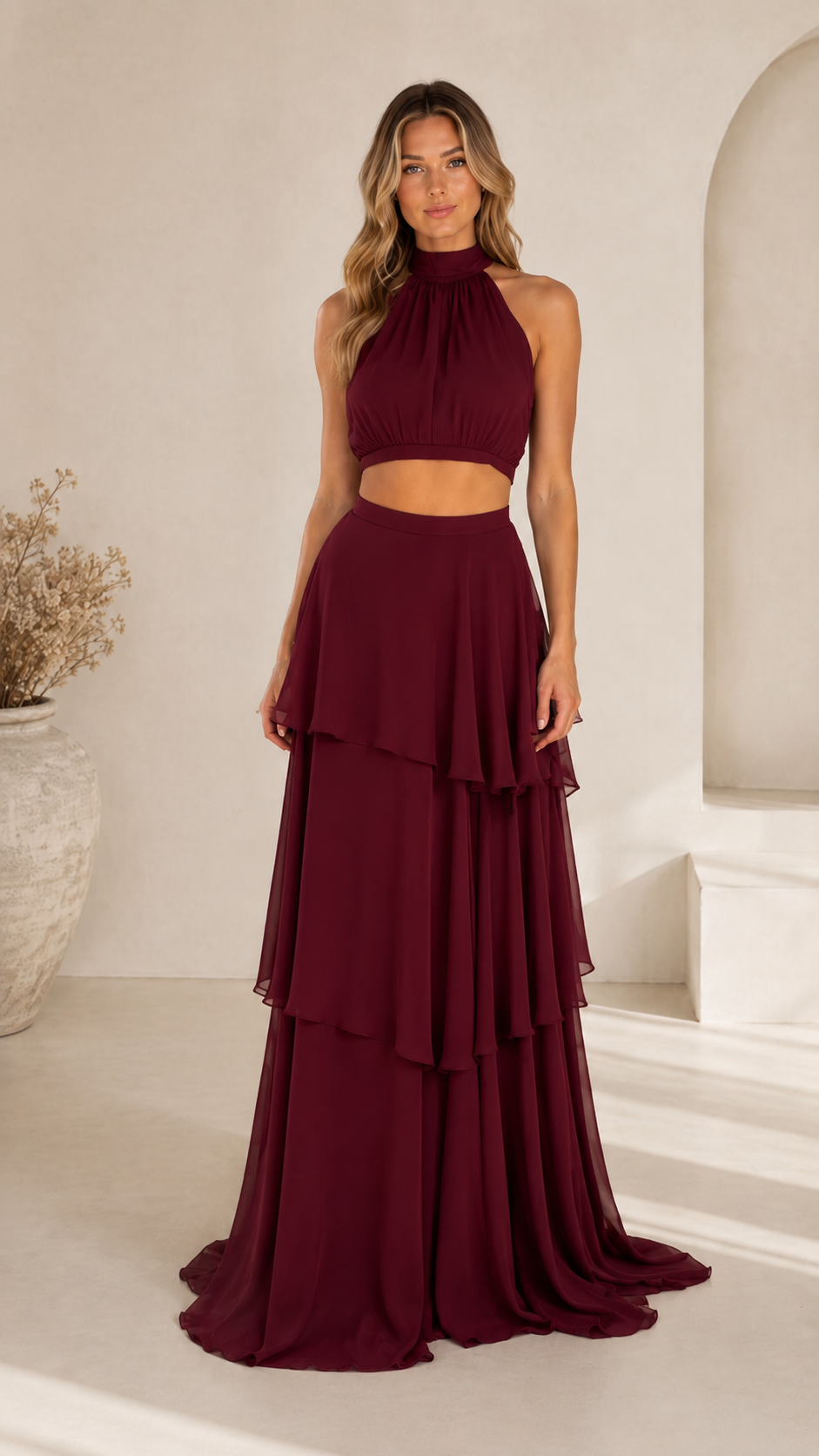 Front view of burgundy halter crop top and flowing layered maxi skirt set