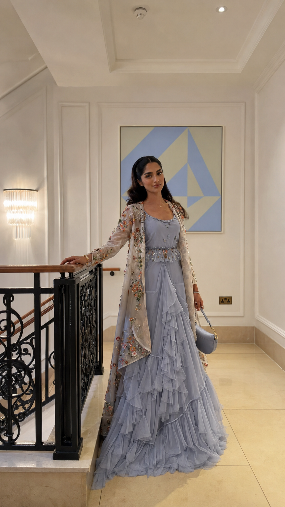 Woman wearing a powder blue ruffle gown with a floral embroidered sheer cape